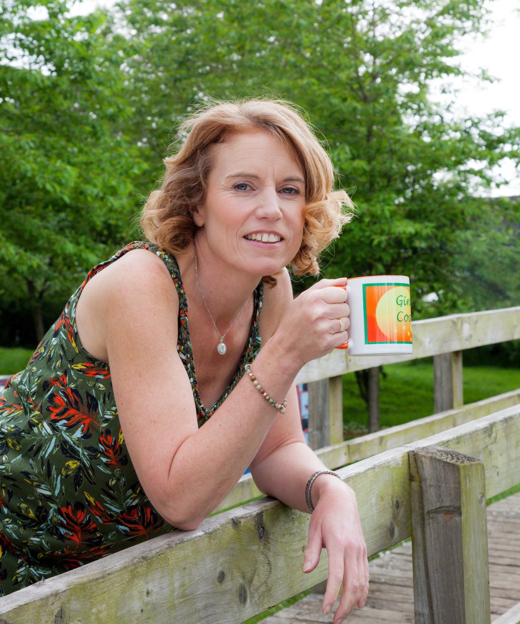 Gina Dallison, chronic illness life coach, outdoors with a mug